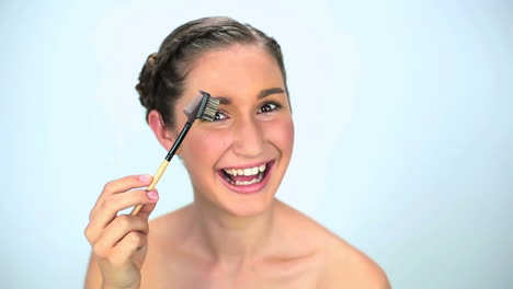 Smiling-young-woman-brushing-her-eyebrow