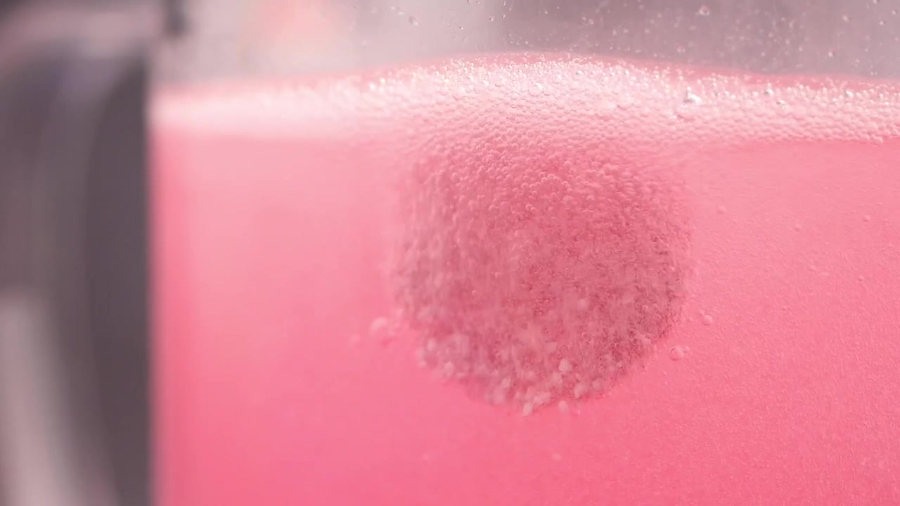 Tableta efervescente disolviéndose en líquido rosa