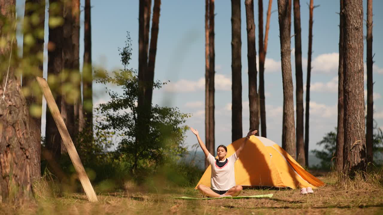 텐트 에 의해 숲 에서 명상 하는 여자