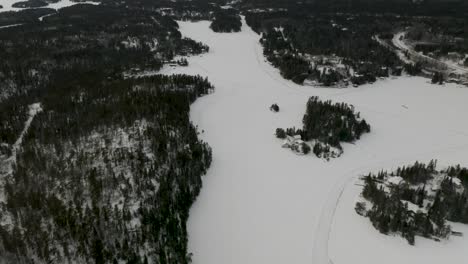 dolly aéreo delante de un lago canadiense congelado en el bosque boreal del norte de canadá