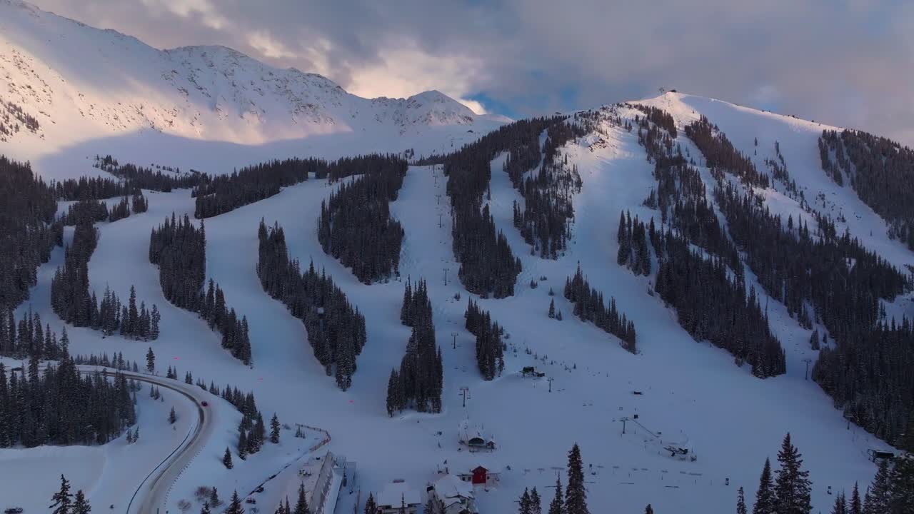 Loveland Pass sunset Arapahoe Basin Basin Abay Ski Resort Colorado aerial drone winter spring last light golden hour groomed ski trail runs chairlift main lodge Base Area parking lot forward pan up