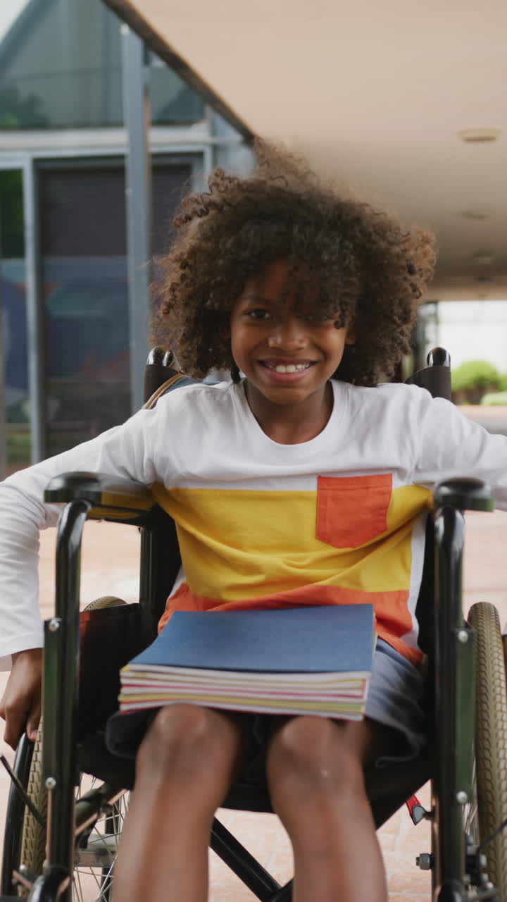 Smiling African American boy in wheelchair, vertical video portrait, corridor, copy space