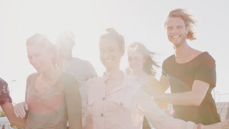 Un-Grupo-De-Jóvenes-Amigos-Al-Aire-Libre-Caminando-Juntos-A-Través-Del-Puente-Contra-El-Sol-Abrasador