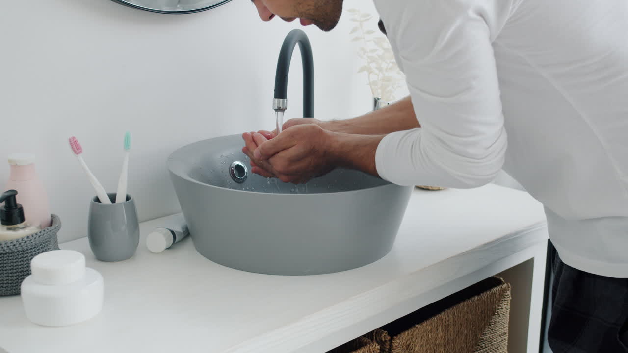 hombre lavándose la cara en el baño