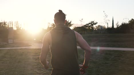 a sportsman runs towards the setting sun, his back is in a tank top