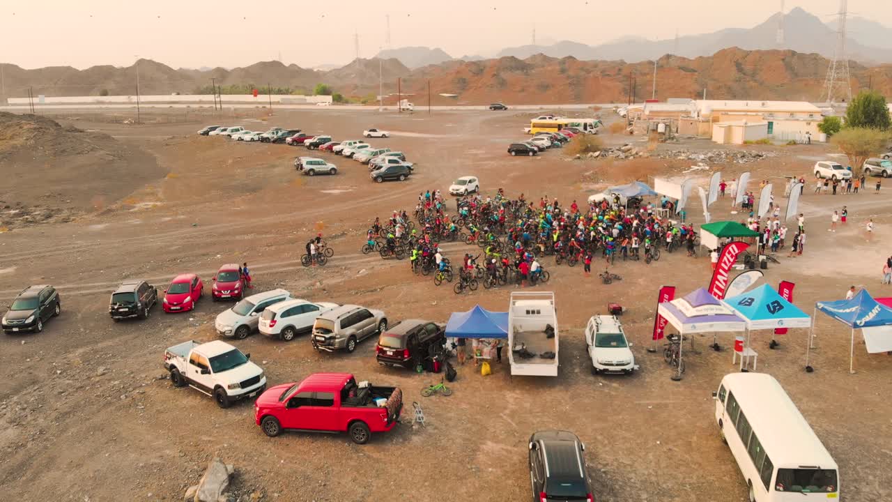 Filipino mountain bikers at the starting line of a cycling race event in a barren area with mountains - AERIAL SHOT