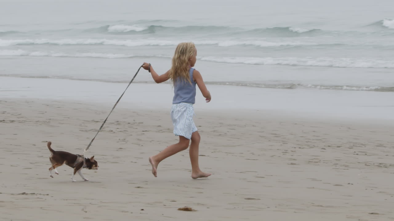 Ragazza che corre con un cane sulla spiaggia