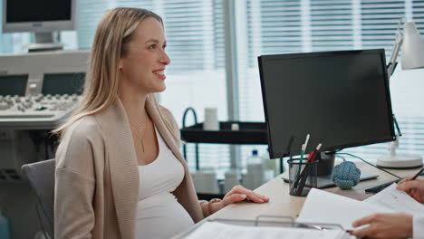 happy expectant visiting gynecologist in clinic. closeup smiling woman talking