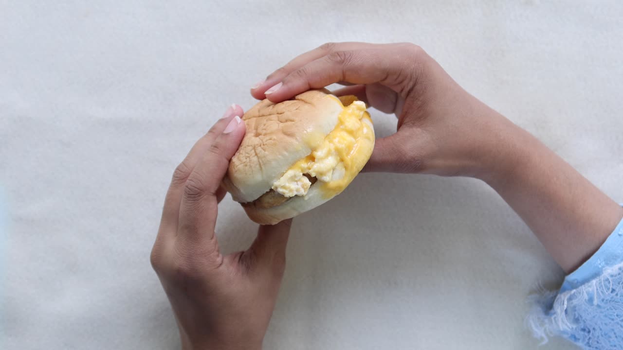mano con un sándwich de queso y huevo