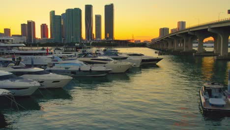 aerial video of yachts at a miami florida marina during sunset, smooth, luxury with view of miami skyline