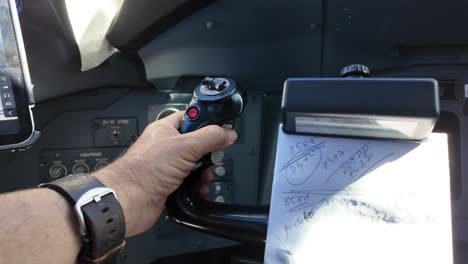 an extreme closeup view of the left hand of white pilot wearing a watch operating the control wheel inside the cockpit of a modern jet. daylight. 4k 60fps.