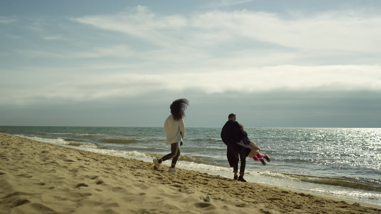 해변에서 즐거운 휴가를 보내는 즐거운 가족. 긍정적인 사람들은 바다에서 놀습니다.