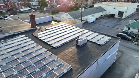 solar panels and an air conditioning unit on top of an industrial building in a small riverfront community at sunset