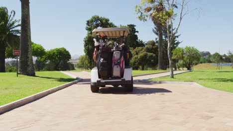 rear view of caucasian senior couple driving a golf cart with clubs on the back at golf course