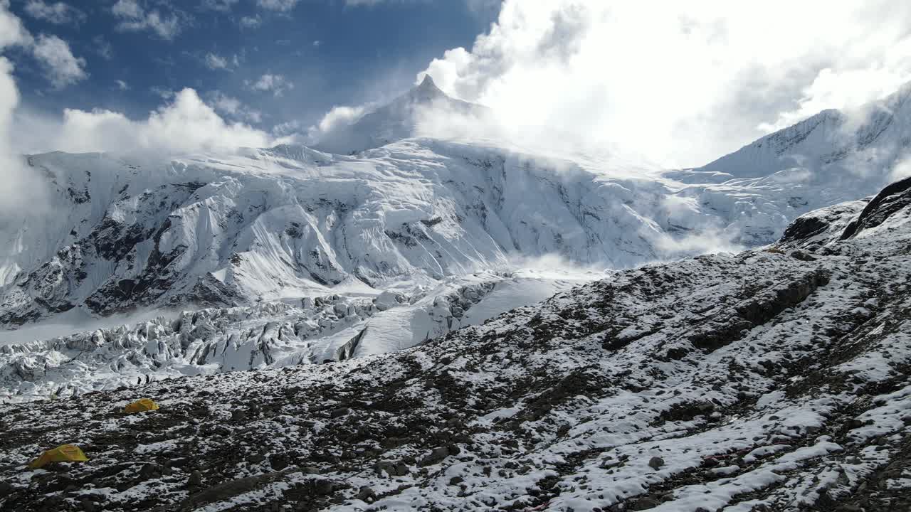 A dramatic drone shot shows the road toward Mount Everest, surrounded by glacier textures and the towering Himalaya. The high-altitude scenery reveals the raw beauty of Nepal’s rugged peaks