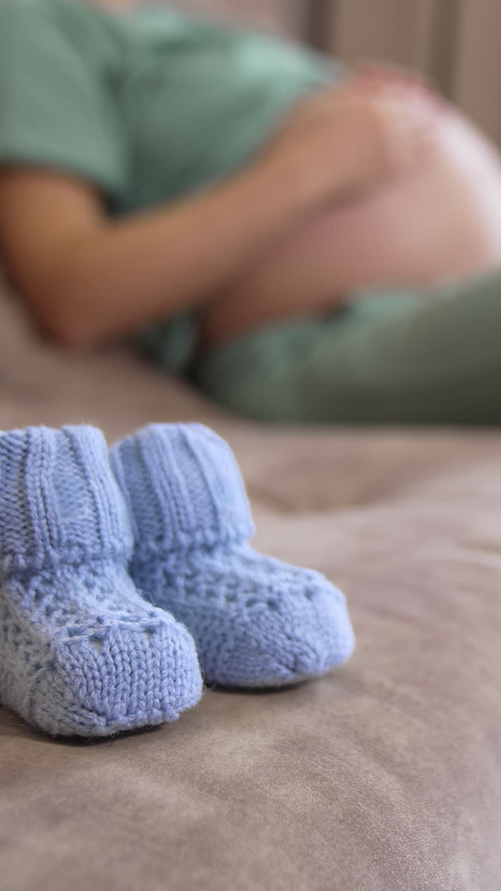 Woman holds baby in pregnant belly. Happy young expecting mother holding baby in pregnant belly