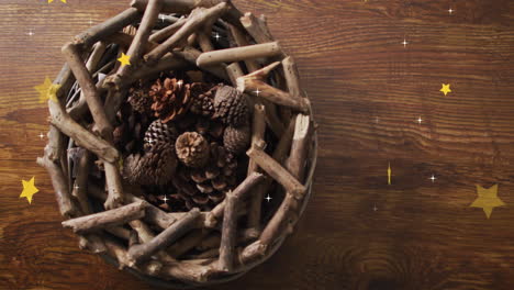animation of stars over wreath with branches and cones on wooden background