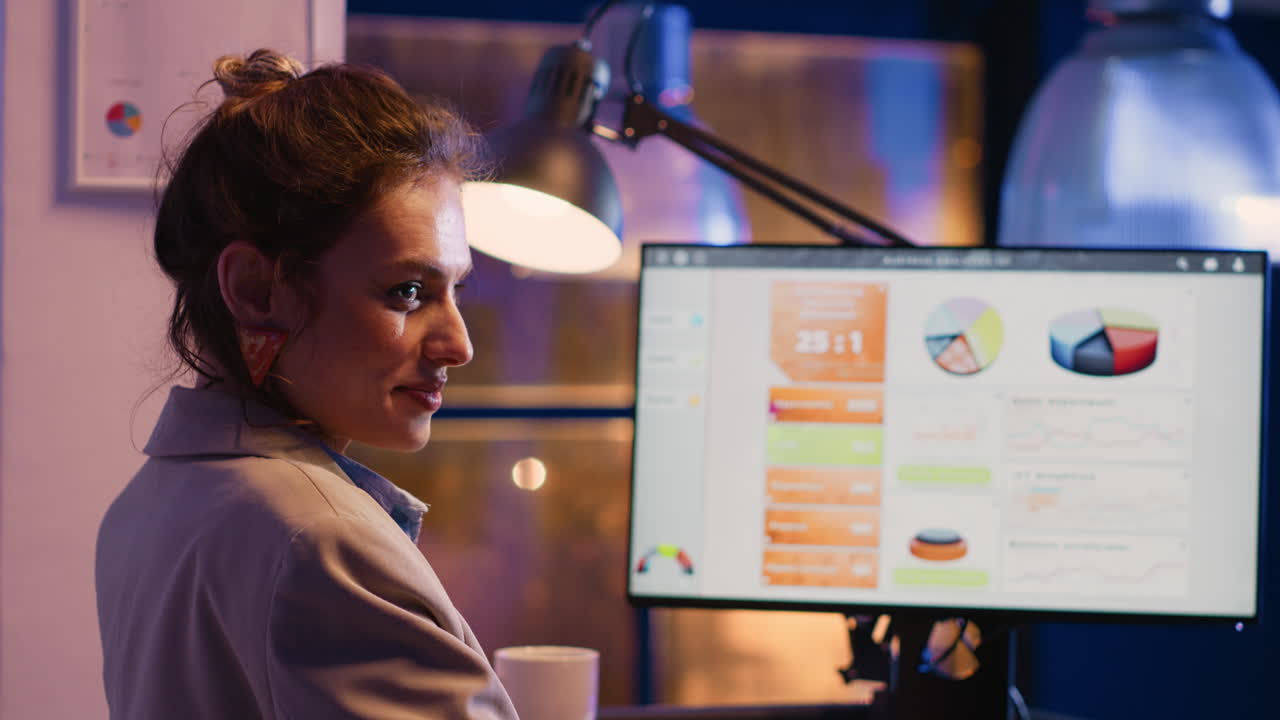 Woman working on computer with data charts at desk