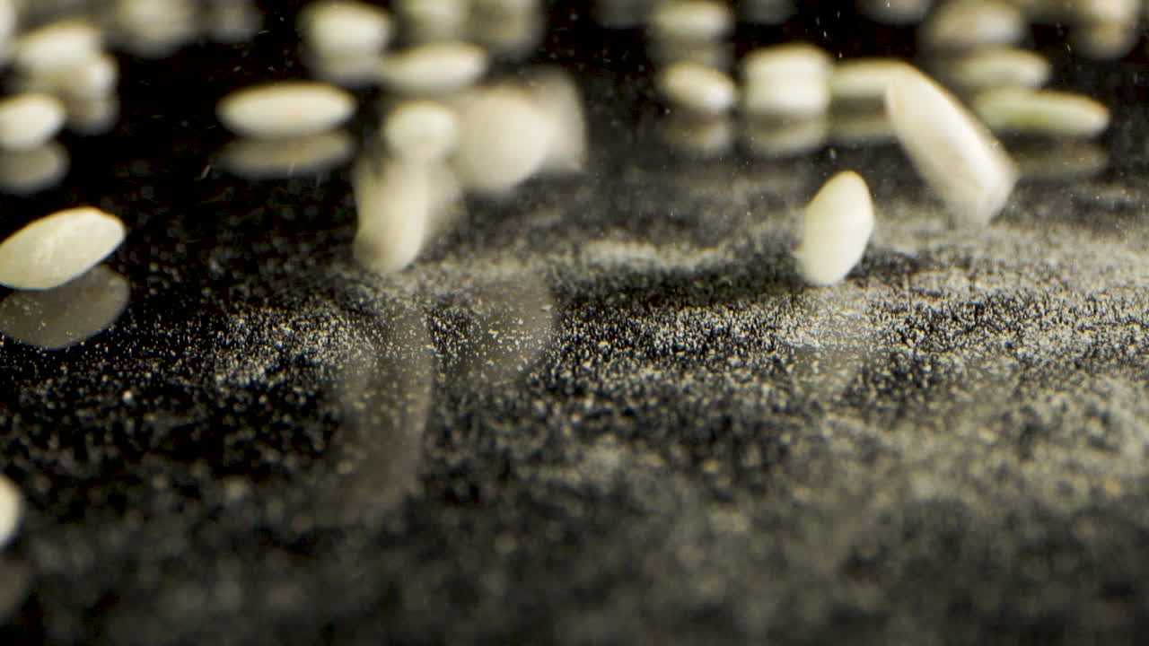 매크로 laowa 렌즈를 마스킹할 때까지 리조또를 위해 쌀을 닫고 검은 표면에 튀는