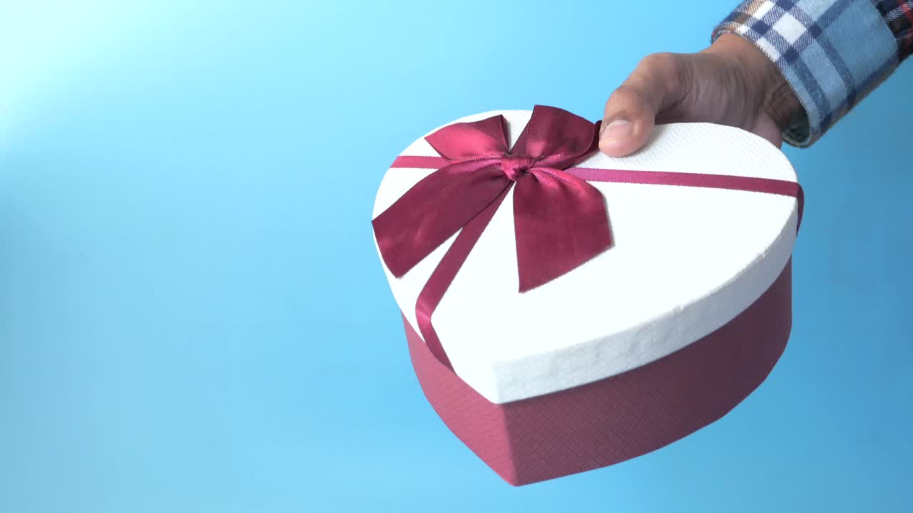 persona que sostiene una caja de regalos en forma de corazón
