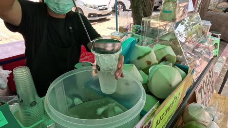 street vendor skillfully pours coconut water into a cup.