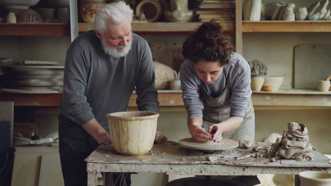 Anziano e giovane adulto che imparano la ceramica