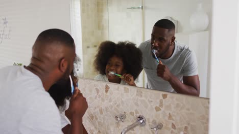 hija afroamericana y su padre mirándose en el espejo cepillándose los dientes juntos en el baño