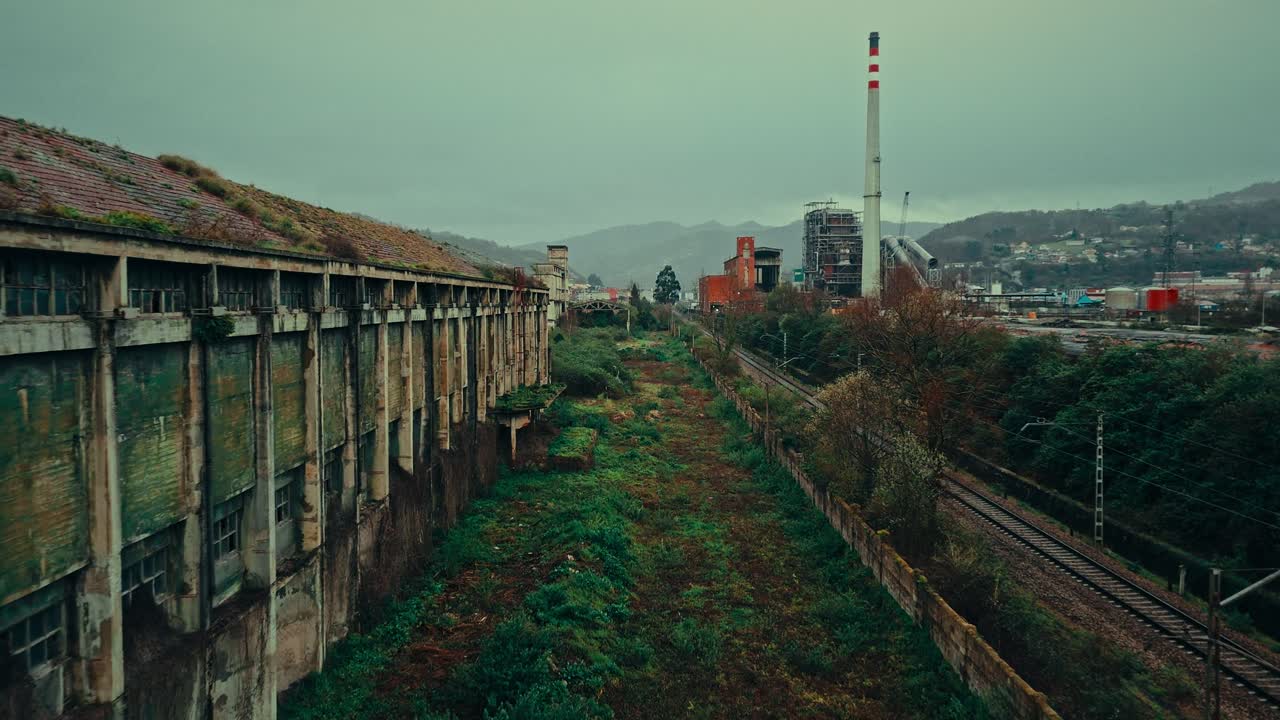 Edificio industriale abbandonato con tetto invaso dalla vegetazione e centrale elettrica attiva