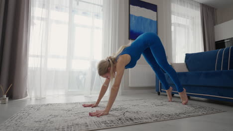 A-woman-trains-at-home-on-the-carpet-in-the-apartment.-Perform-home-exercises.-Fitness-stretching-and-yoga-at-home-remotely.-Remote-training-and-a-healthy-lifestyle