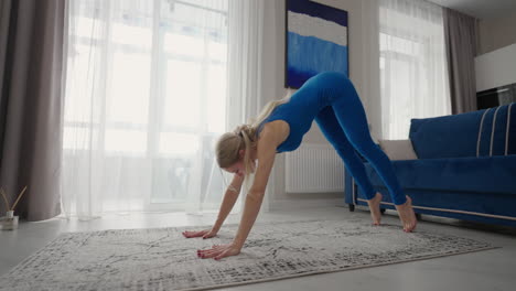 Una-Mujer-Entrena-En-Casa-Sobre-La-Alfombra-Del-Apartamento.-Realizar-Ejercicios-En-Casa.-Estiramientos-Físicos-Y-Yoga-En-Casa-De-Forma-Remota.-Entrenamiento-Remoto-Y-Un-Estilo-De-Vida-Saludable