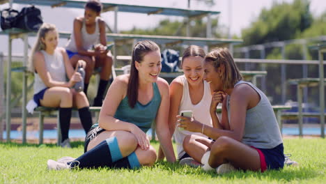 amigos mirando un teléfono en un campo de deportes