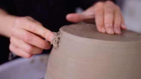 potter shaves pottery on pottery wheel