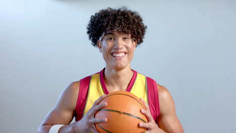 young biracial man holding a basketball