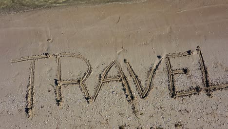 static shot of travel written in the sand at an angle