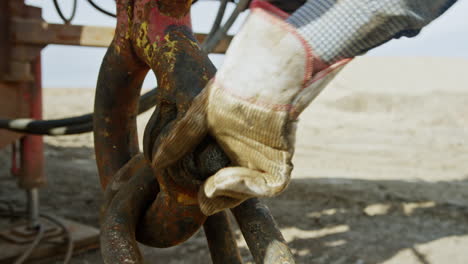 worker's hand wearing protective glove tightening the big metal nut. setting the equipment for drilling gas and oil. close up.