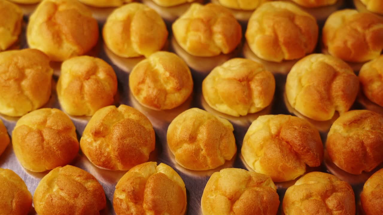 Motion above delicious fresh eclair buns on baking tray