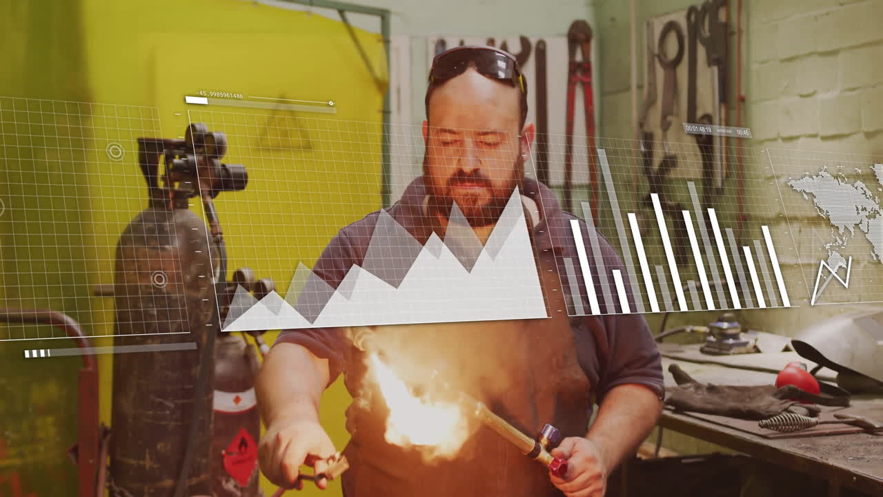 Manufacturing metalworker using blowtorch at workshop, displaying floating chart grid map overlays