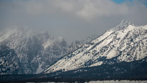 time lapse, mountain range and snow capped peaks under clouds at early winter