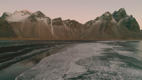 Felsiger,-Schneebedeckter-Vestrahorn-Berg-Und-Stokksnes-Sonnenaufgang,-Meereswellen,-Luftumkehransicht