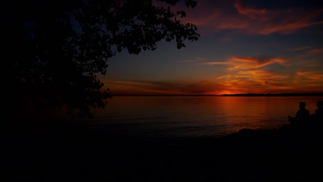 Lapso-De-Tiempo-De-Una-Puesta-De-Sol-Naranja-Entre-La-Silueta-De-Un-árbol,-En-La-Playa-De-Britannia,-Ottawa