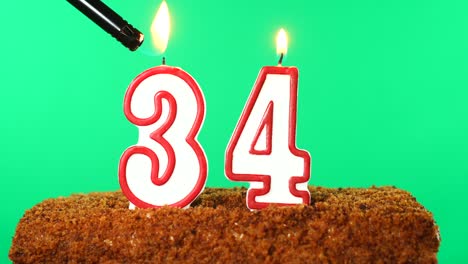 cake with the number 34 lighted candle. chroma key. green screen. isolated