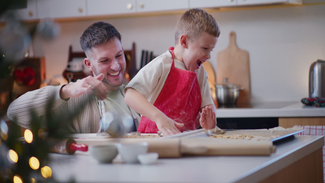 Junge und Vater spielen und albern beim Plätzchenbacken herum