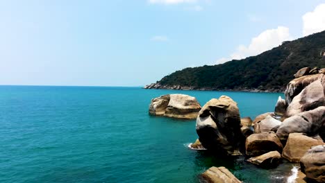 An-orbit-aerial-drone-shot-of-Haad-Tian-beachfront-showing-the-boulders,-white-sandy-beach,-and-the-crystal-blue-clear-waters-of-the-Andaman-Sea-in-Koh-Tao-island,-in-Surat-Thani-province-in-Thailand