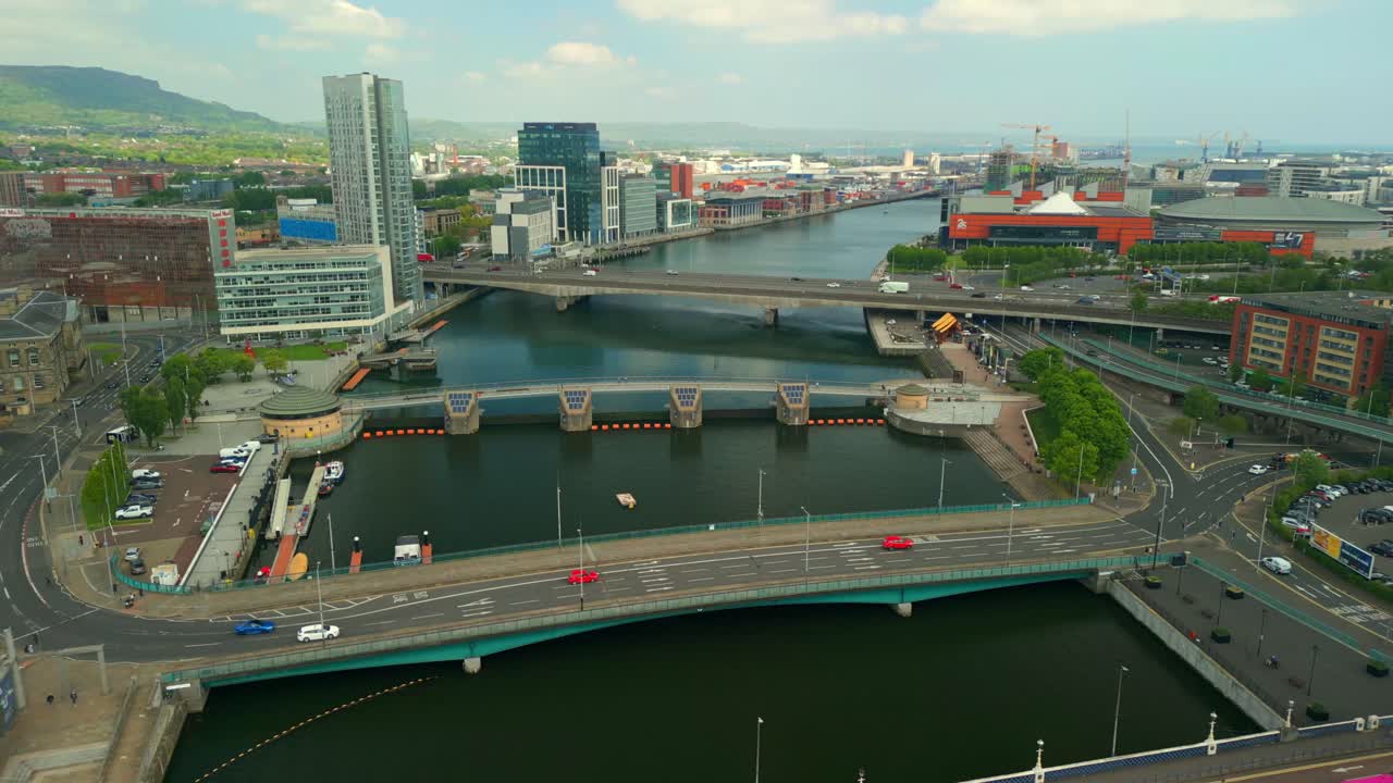 Reversing overhead aerial video of the River Lagan and the surrounding area in Belfast City Centre, Northern Ireland, UK on a bright and sunny day. Filmed in 4K, 60FPS and in Rec709 Color.