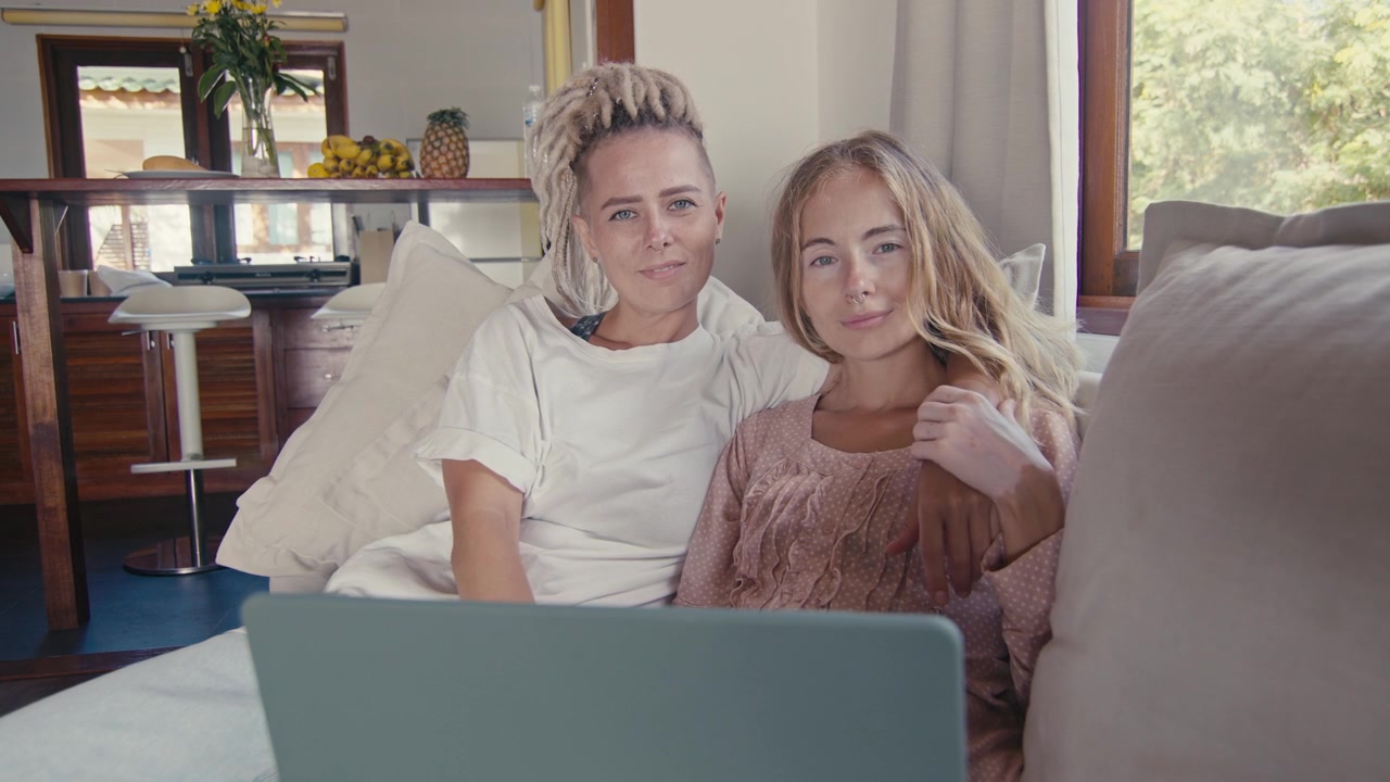 Dos mujeres sentadas juntas en un sofá usando un portátil