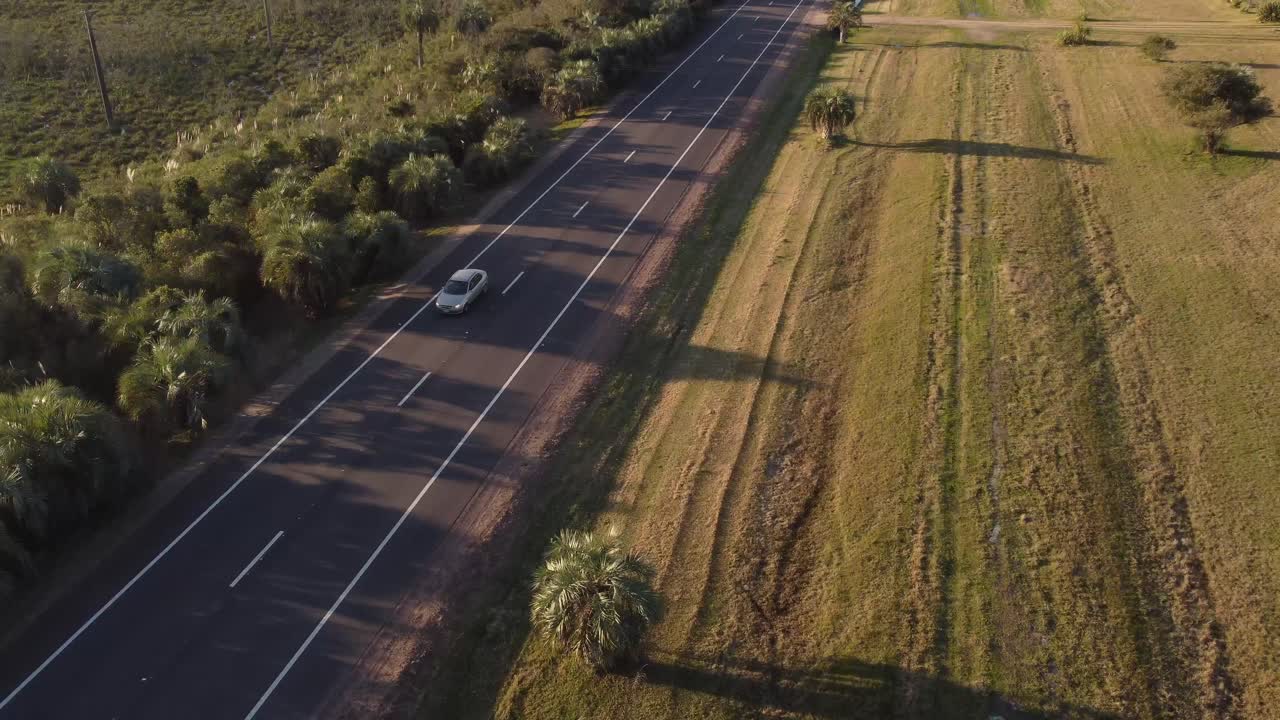 toma de un dron de un camión conduciendo por un camino rural al atardecer en uruguay - viajando en un área escénica de américa del sur