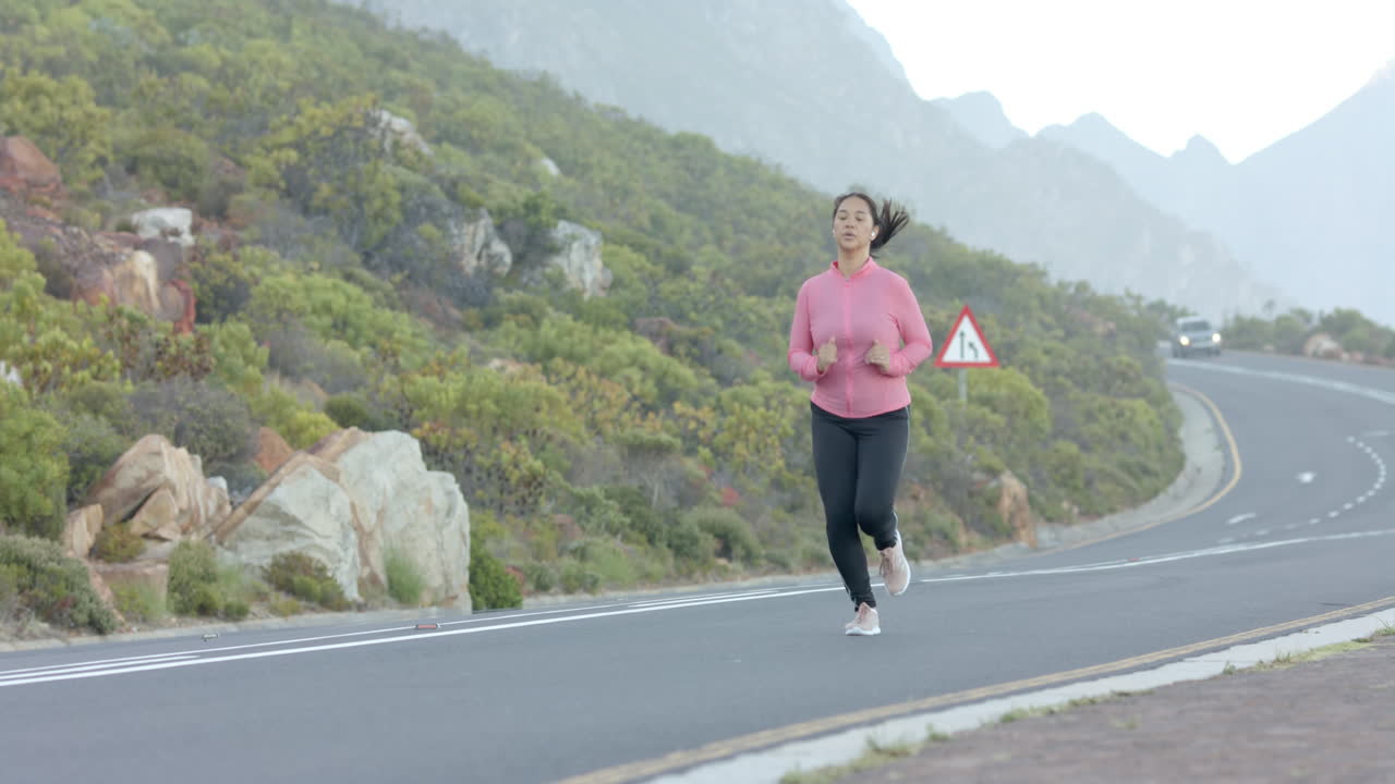 Jogging on mountain road, woman in pink sweatshirt exercising outdoors, copy space