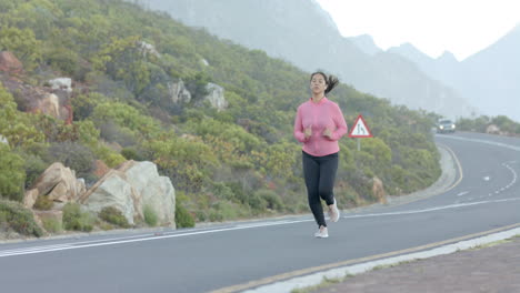 jogging on mountain road, woman in pink sweatshirt exercising outdoors, copy space