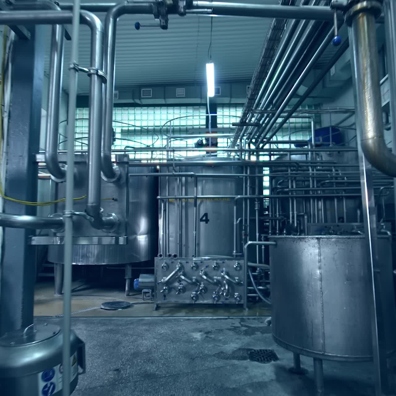 Moving along the impressive and complicated milk factory equipment. Metal pipelines and tanks connected with each other into a system. Dolly shot