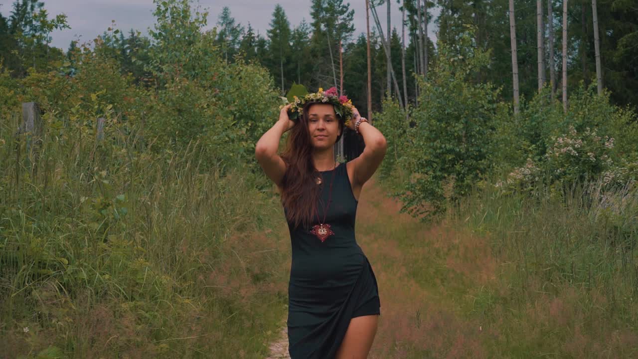 Donna hippie spensierata che indossa una corona di fiori in mezzo alla foresta, in slow motion.